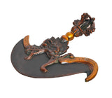 Brass dorje flaying knife close-up: orange-gold handle with carved figure and dark blade