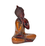 Brass meditating Buddha figurine in seated pose, red and golden tones