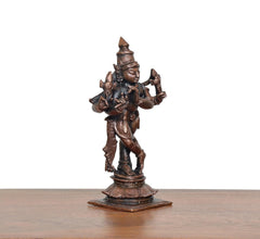 Side view of copper-bronze Krishna playing flute statue on decorative base