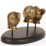Two brass head idols back/side view on dark circular base with stems