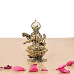 Back view of brass Maa Saraswati statue with halo, seated on lotus