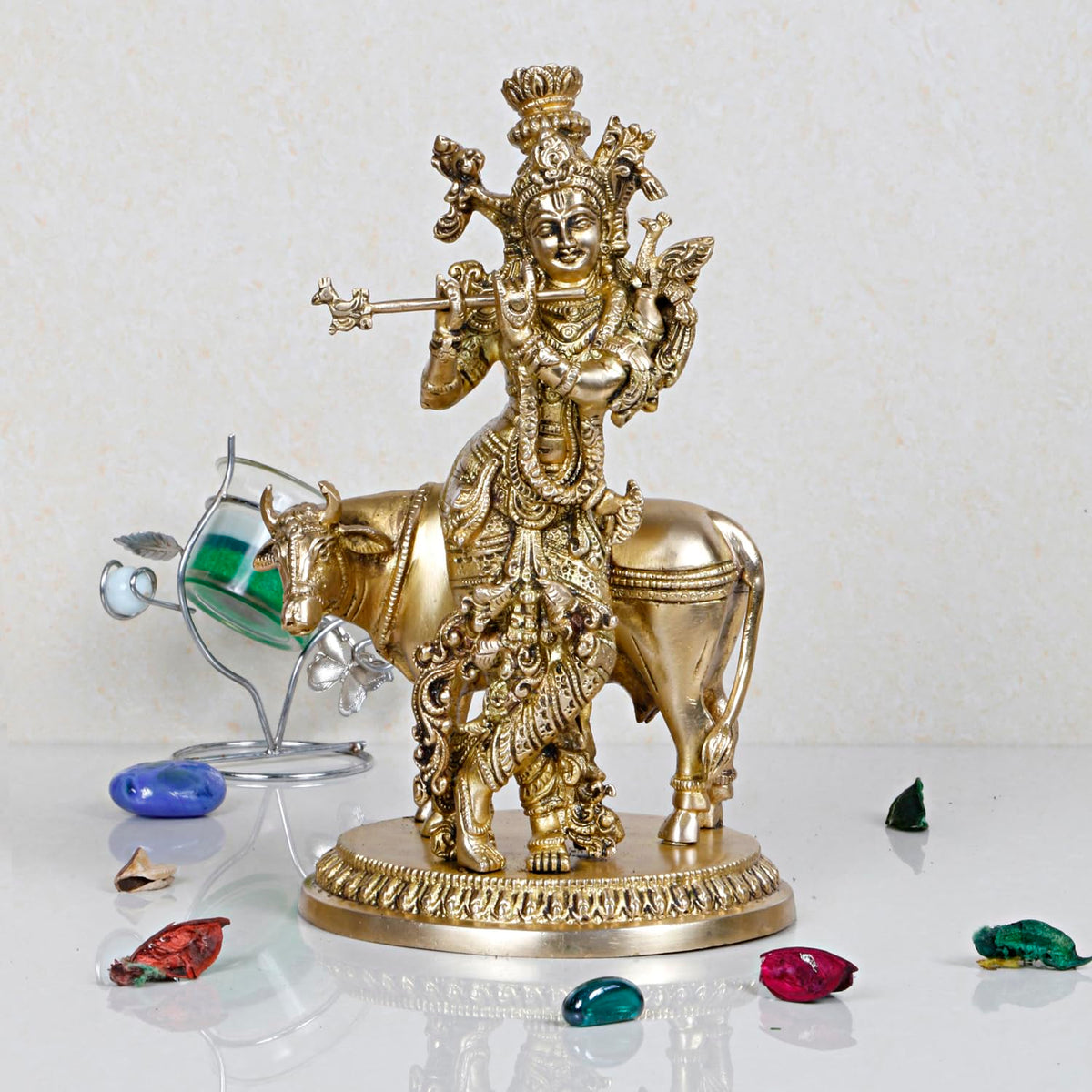 Brass Krishna statue on cow, Krishna holding flute, ornate gold-tone details