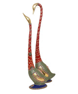 Two swan statues with tall red curved necks, green mosaic bodies, blue round bases