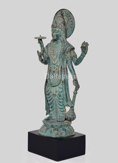 Side view bronze Lord Vishnu idol with circular halo, layered robe, holding a discus