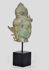 Bronze Vishnu head idol side profile with calm eyes, ornate crown, on black stand