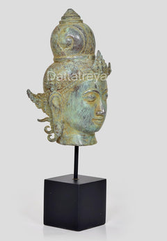 Bronze Vishnu head idol side profile with calm eyes, ornate crown, on black stand