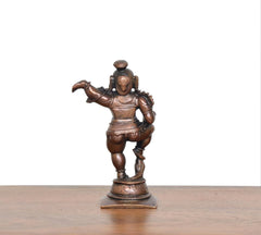 Copper Bal Krishna showpiece with laddu, three-quarter back view on base