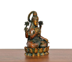 Lakshmi brass idol from side, three-quarter view showing crown, jewelry, and lotus base