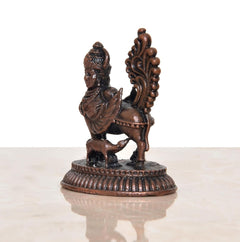 Copper Kamadhenu cow statue side view with wings, ornate relief, round base.