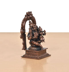 Side view of copper Lakshmi Narasimhar idol with raised hands and arch backdrop