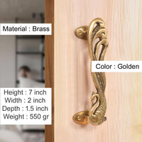 Golden brass peacock door handle pair, mounted on a light wood door