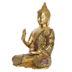 Brass Buddha statue angled view; seated posture; red and blue inlay details on robe