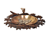 Brass decorative urli bowl with butterfly and bird figurine resting on a dark floral ring