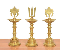 Front view of brass diya shankh oil lamp trio with emblem tops and flared bowls