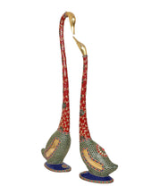 Back view of kissing swan couple statues, red necks and green mosaic bodies, blue bases