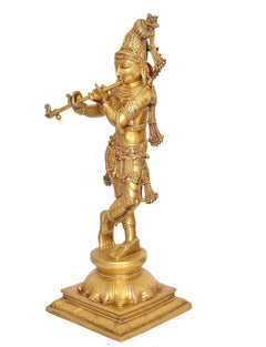 Side view of brass Krishna playing flute idol statue on round pedestal