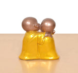 Resin laughing Buddha sculpture, back/side view of two monks embracing in yellow robes