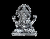 Brass Ganesha idol seated with four arms raised, detailed halo and pedestal.