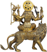 Durga deity idol statue from behind, seated on lion with weapons raised