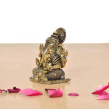 Brass Lord Ganesha idol, side view with ornate crown and patterned base on a stand