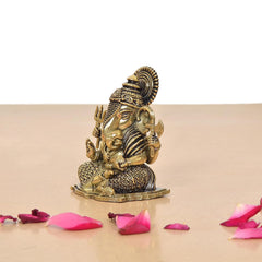 Brass Lord Ganesha idol, side view with ornate crown and patterned base on a stand