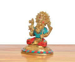 Three-quarter view of brass goddess statue: gold crown, teal top, red patterned skirt, holding trident.
