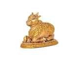 Side view of seated Nandi bull statue with gold ornaments and patterned base