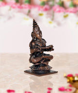 Copper Maa Annapurna statue, side view, seated holding an instrument, 3.5 in tall