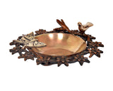 Brass urli bowl with centered butterfly motif and bird details on a copper-toned floral frame