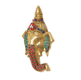Brass Ganesha head wall hanging, three-quarter view with red patterned trunk and blue gems