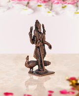 Copper standing deity murti side view with ornate jewelry and peacock near feet