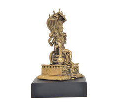 Vishnu idol from side view with crown-like canopy, seated figure and gold-tone base