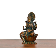 Lakshmi brass idol side view, raised hands, teal-green garment on lotus base