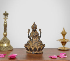 Copper Lakshmi idol, seated figure with four arms, ornate jewelry and lotus base