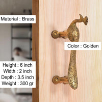 Gold brass peacock door handle on wood panel, screw-mounted bar handle