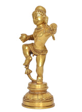 Side view of brass-tone baby Krishna dancing statue, smiling face, raised left arm