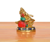 Brass Ganesha statue blowing conch shell, close side view, red and green ornaments