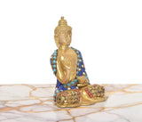 Side view of brass Buddha idol in Abhaya mudra, blue robe with turquoise accents