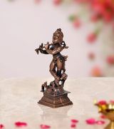 Side view dark bronze Krishna figurine playing flute, with cow at feet, square base