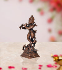 Side view dark bronze Krishna figurine playing flute, with cow at feet, square base