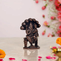 Lakshmi Narasimha copper statue side view with raised arms and carved detailing on base