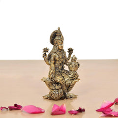 Brass Lakshmi idol side view, detailed crown and jewelry, seated on lotus pedestal