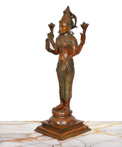 Standing brass Lakshmi murti angled view, four arms with lotuses, ornate attire