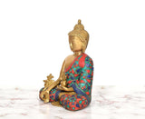 Side view of brass Buddha statue with multicolor robe and blessing-hand pose