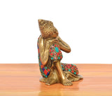 Back view of brass seated Buddha idol with multicolor mosaic robe and ornament