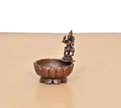 Krishna urli bowl showpiece side view, scalloped copper basin with central deity figure