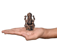 Copper Ganesha idol in hand, small seated statue with crown and four arms