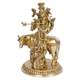 Brass Krishna statue on cow, front view of ornate outfit and crown, gold tone