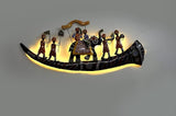 Iron wall decor with warm glow along curved base and colorful central figure