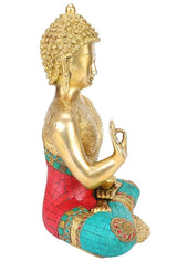 Brass Buddha statue in profile, seated with joined hands; red and teal mosaic base